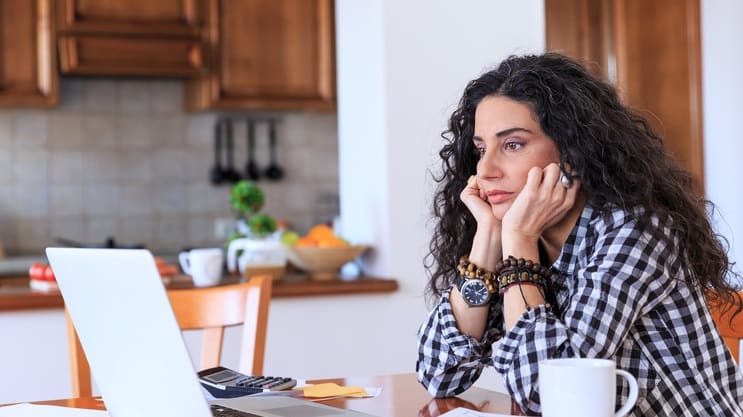 A woman sitting at a table with a laptop in front of her.