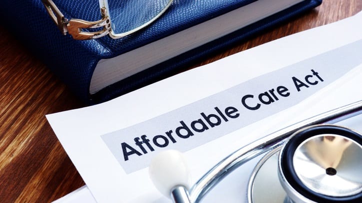A stethoscope sits on top of a paper with the word affordable care act.