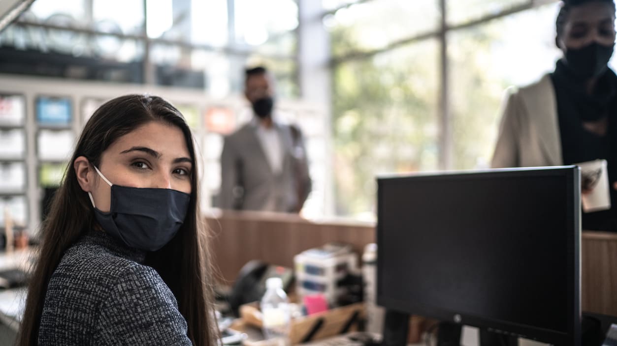 A woman wearing a face mask while working in an office.