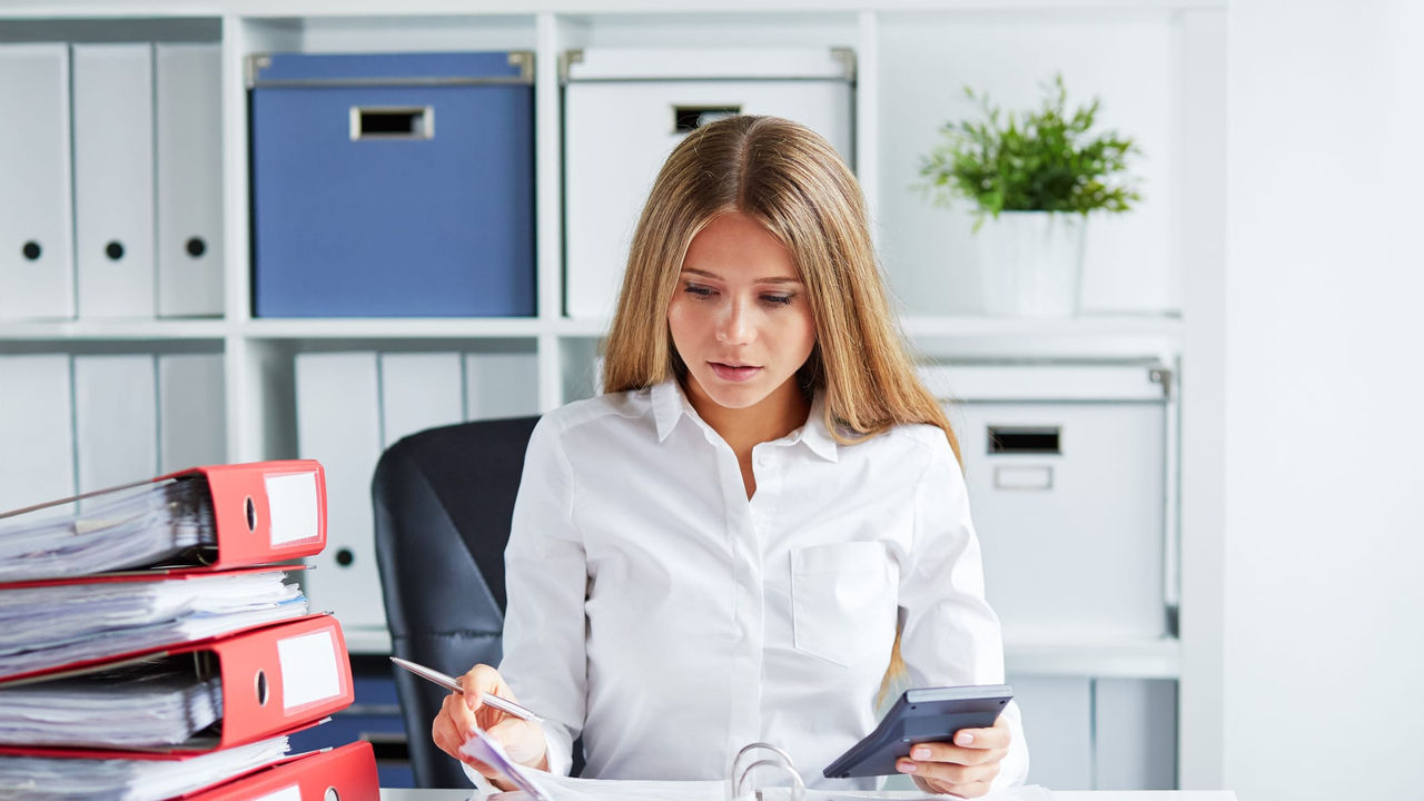 A woman is sitting at a desk and looking at her phone.