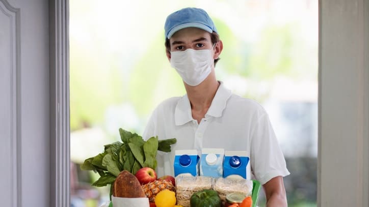 A man in a mask holding a basket of food.