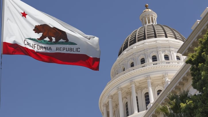 A california flag flies in front of the california capitol building.