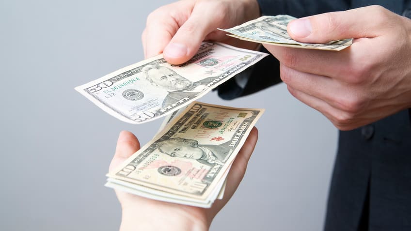 A businessman handing money to a woman.