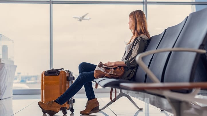 A woman sitting on a bench in an airport waiting for a plane.