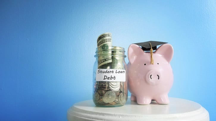A piggy bank next to a jar of money and a graduation cap.