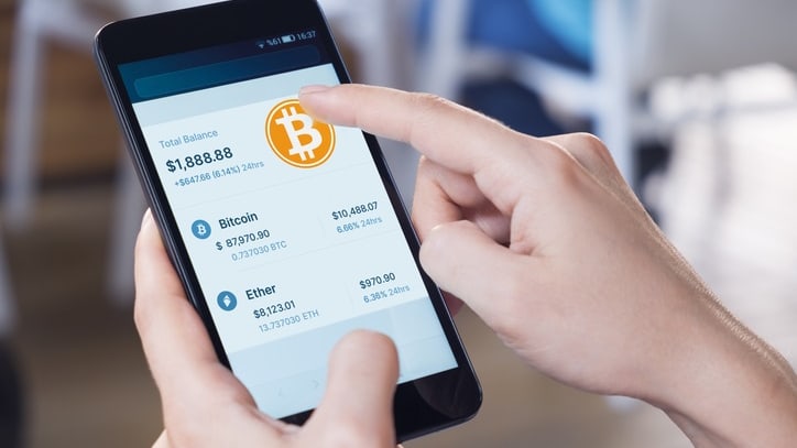 A person holding a smartphone with bitcoin on the screen.