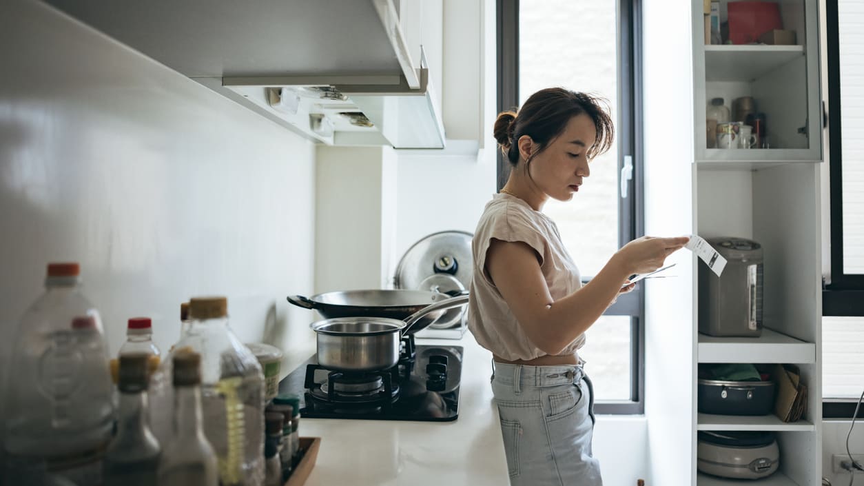 A woman in a kitchen looking at her phone.