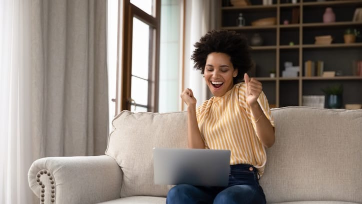 A woman is sitting on a couch and using a laptop.