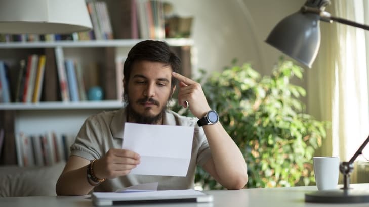 A man is sitting at a desk reading a letter.