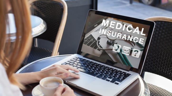 A woman using a laptop with medical insurance on it.