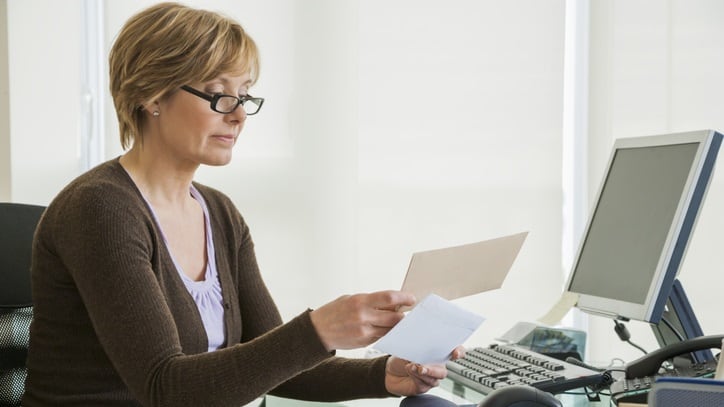 A woman sitting at a desk with a letter in front of her.