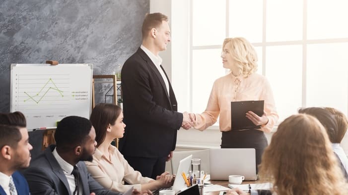 A group of business people shaking hands in a meeting room.