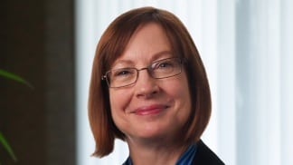 A woman wearing glasses and a blue tie.