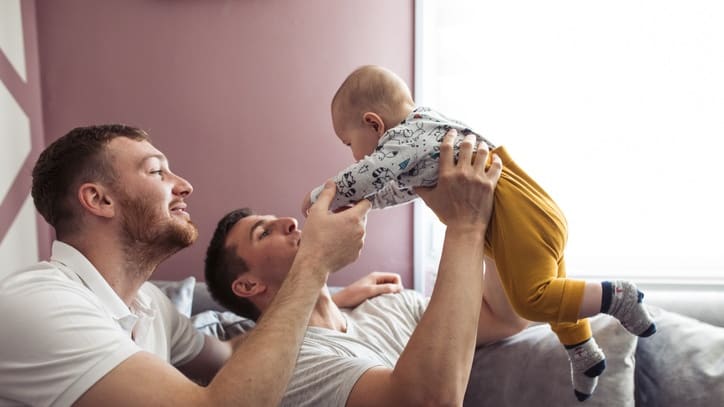 Two dads playing with their baby