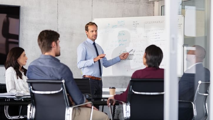 A group of business people in front of a whiteboard.