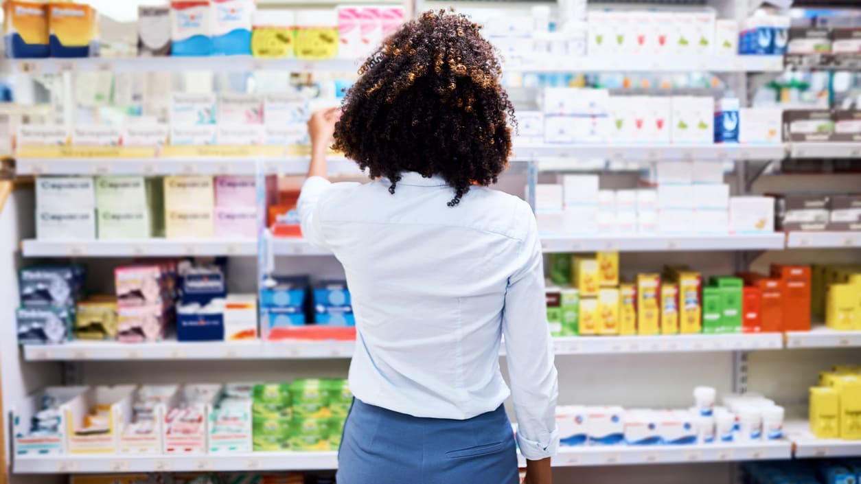 A woman in a pharmacy looking at the shelves.
