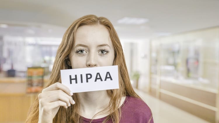 A woman holding up a sign that says hipaa.