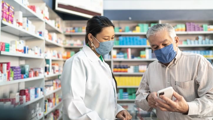 A man and woman in a pharmacy looking at a tablet.