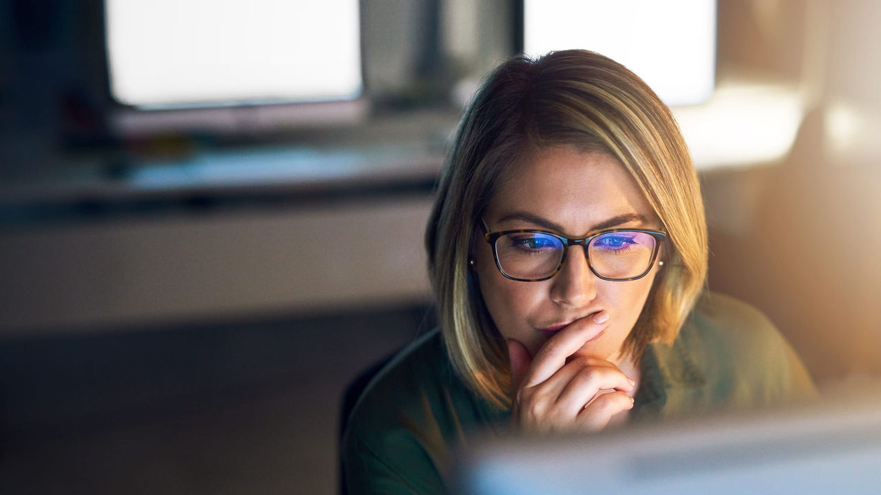 A woman wearing glasses is looking at a computer screen.