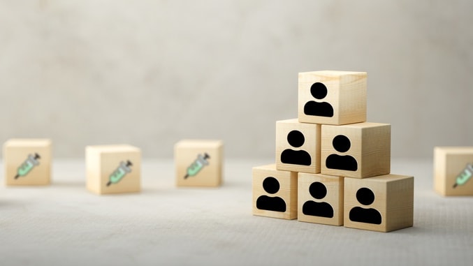 A stack of wooden blocks with person icons on them next to scattered wooden blocks with syringes on them