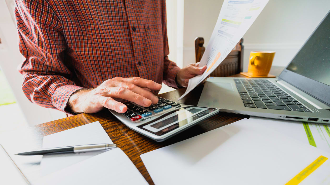 A man is using a calculator at a desk.