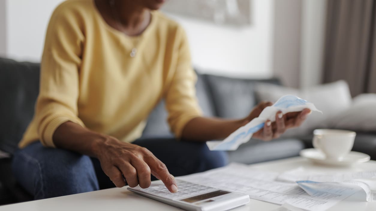 A woman sitting on a couch with a calculator and papers.