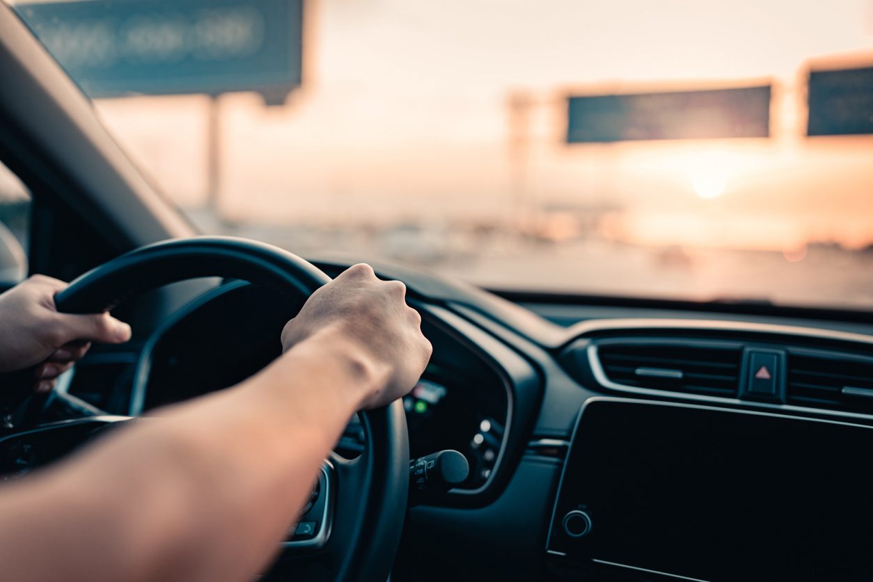 closeup of a driver's hands on a steering wheel in a car