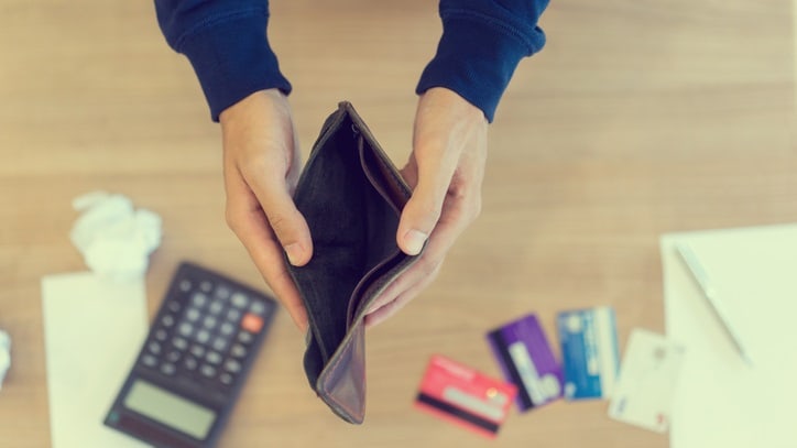 A person holding a wallet on a desk.