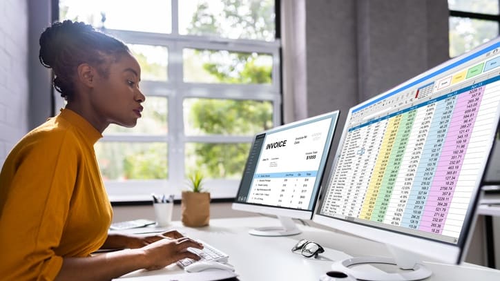 A woman working at her desk with two monitors.