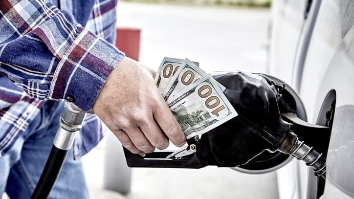 A man is putting money into a gas pump.