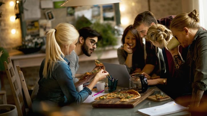 A group of people sitting around a table eating pizza.