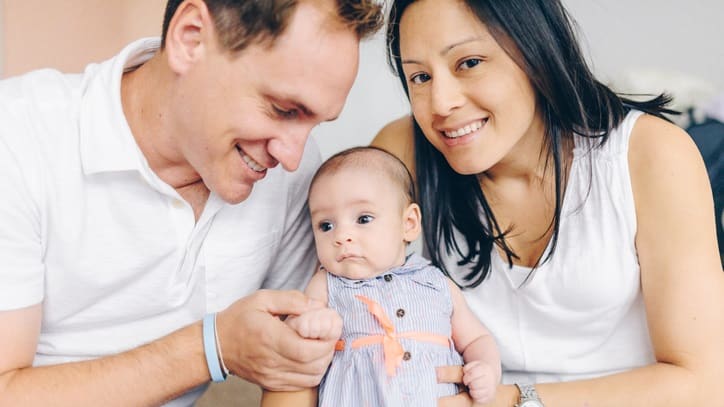 A man and woman are smiling while holding a baby.