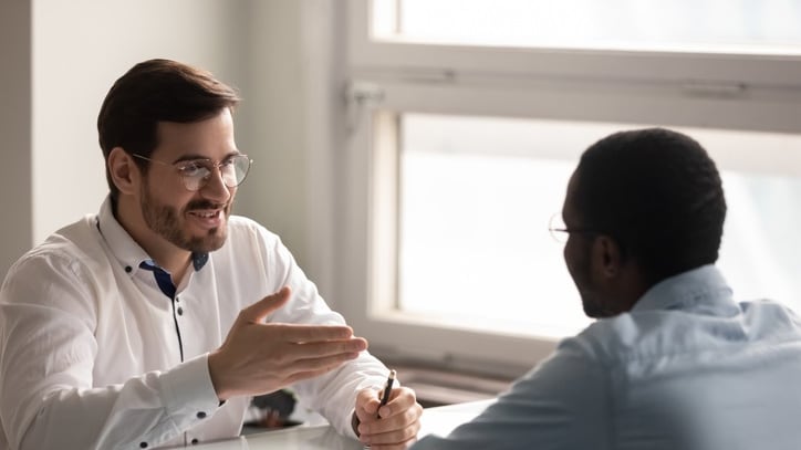 A man is talking to another man in an office.