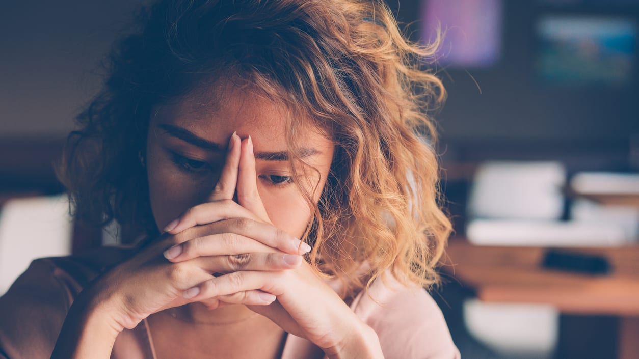 A woman with her hands on her face in a restaurant.