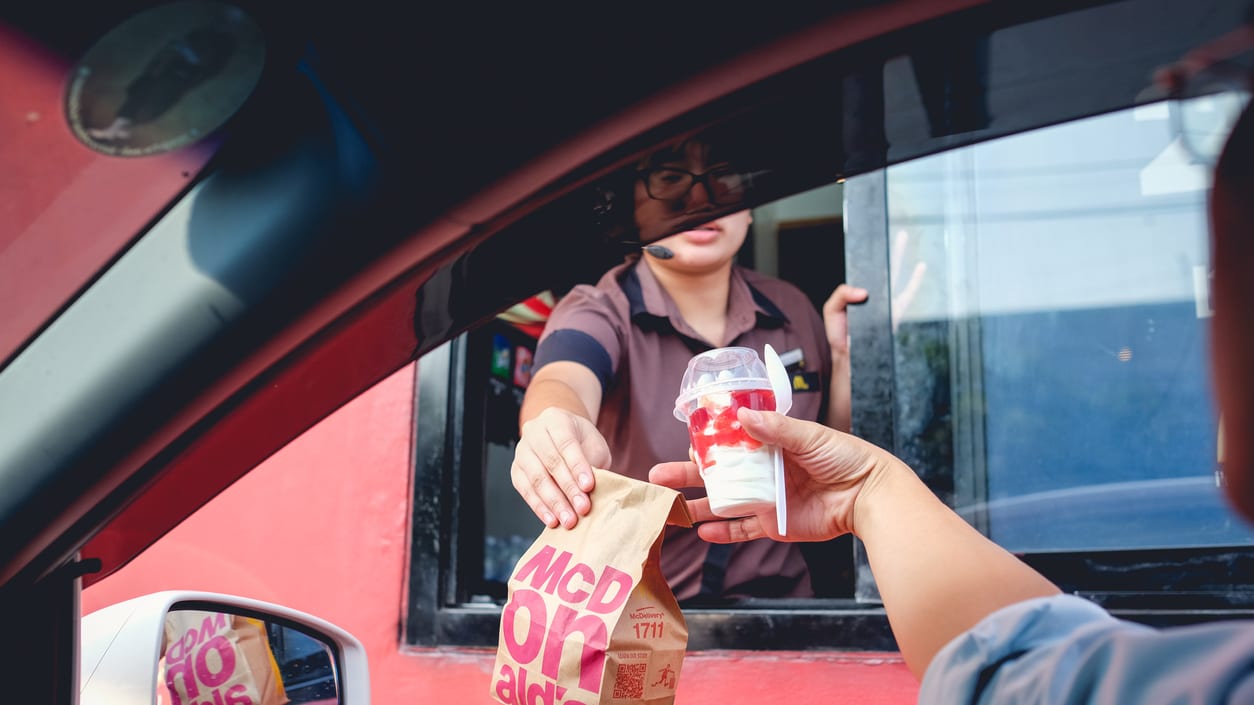 A man giving a bag of food to a woman in a car.