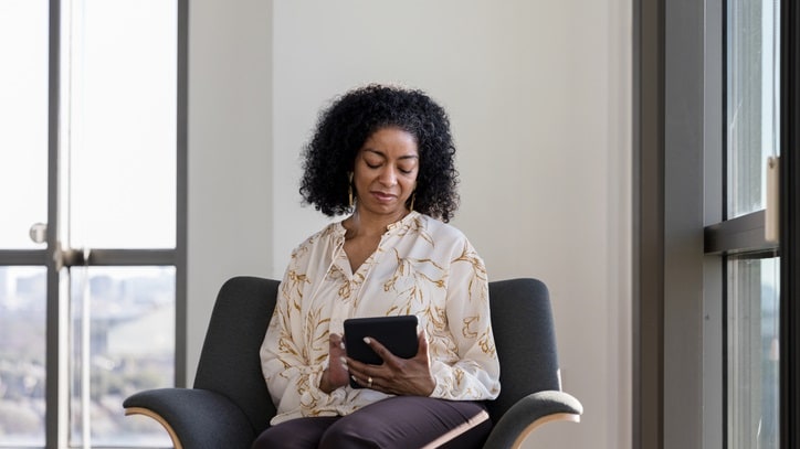 A woman sitting in a chair using a tablet computer.