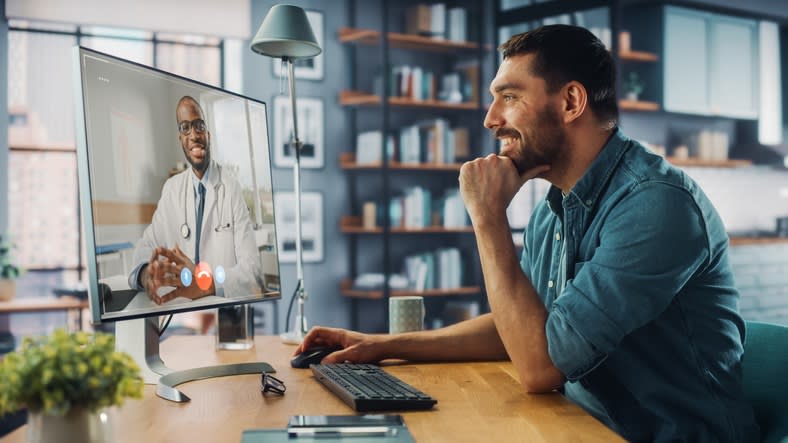 A man is watching a doctor on a computer screen.