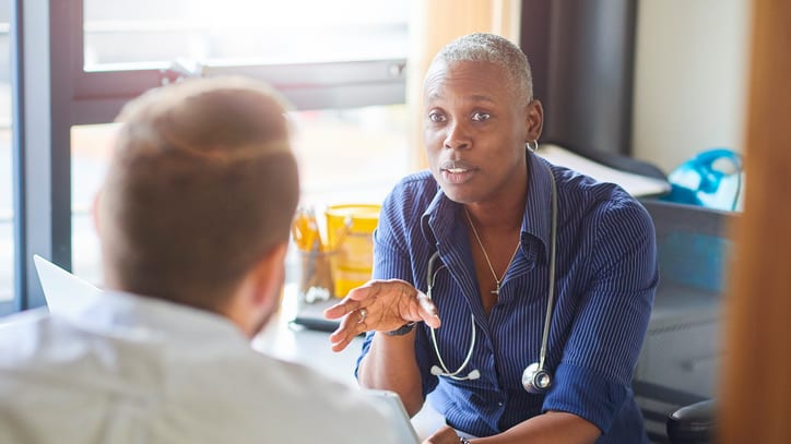 A doctor talking to a patient at a desk.