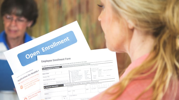 A woman holding a paper with the word open enrollment.