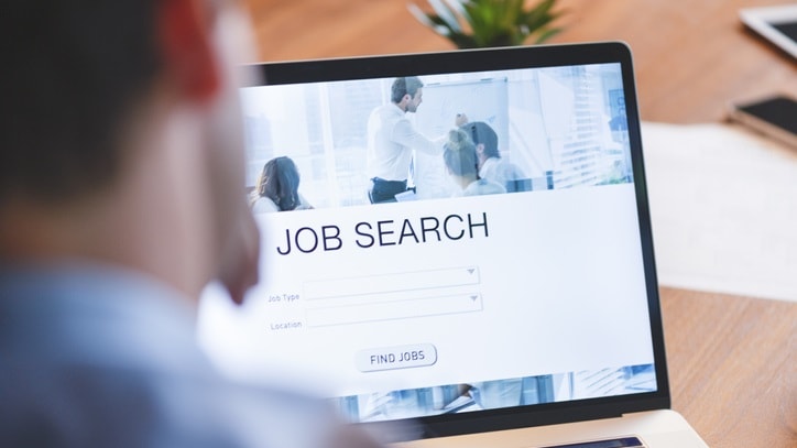 A man is looking at a job search page on a laptop.