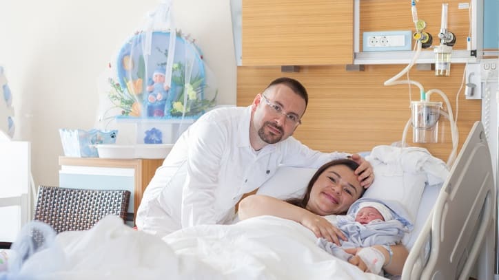 A man and woman are laying in a hospital bed.