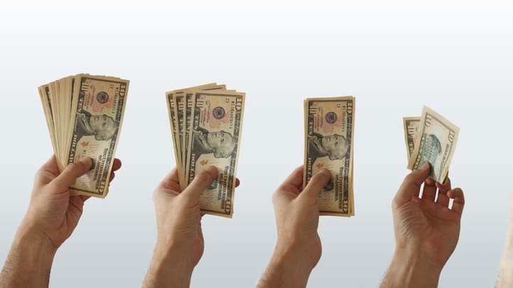 A group of hands holding dollar bills in front of a white background.