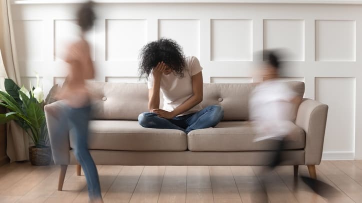 Three people sitting on a couch in a living room.