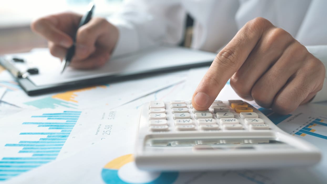 A man is holding a calculator and a pen.