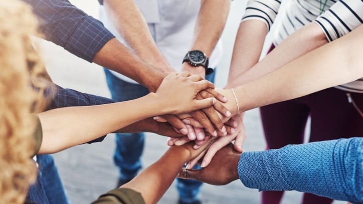 A group of people putting their hands together in a circle.