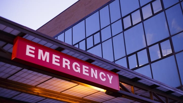 A hospital emergency sign is lit up at dusk.