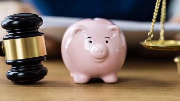 A piggy bank and a gavel on a table.