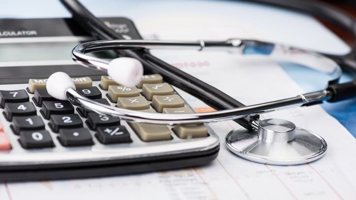 A stethoscope and a calculator on top of a sheet of paper.