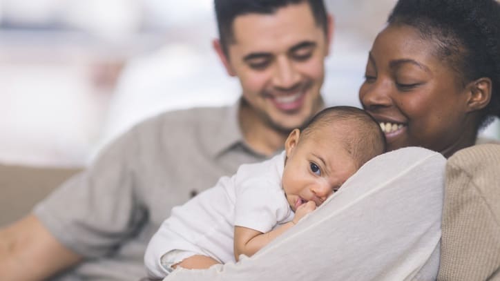 A man and woman are holding a baby on a couch.