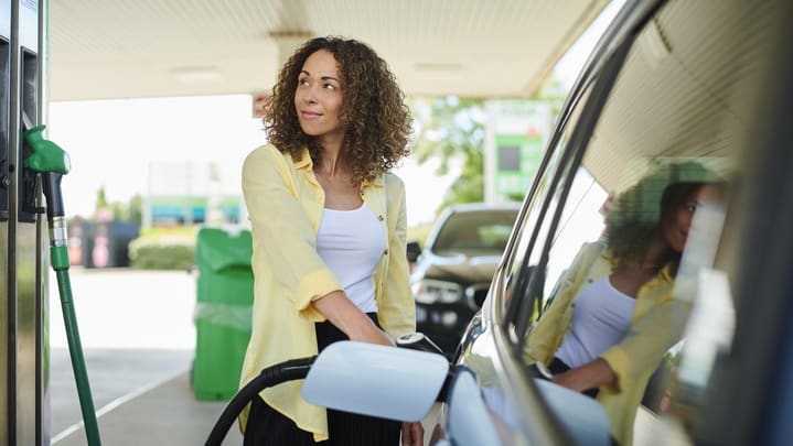 A woman filling up her car at a gas station.